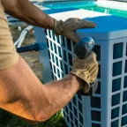 Why Pool Heaters Stop Working After Winter: Common Problems Explained by Pool Repair Companies Technician from pool repair companies inspecting and repairing a pool heater beside a swimming pool after winter issues.